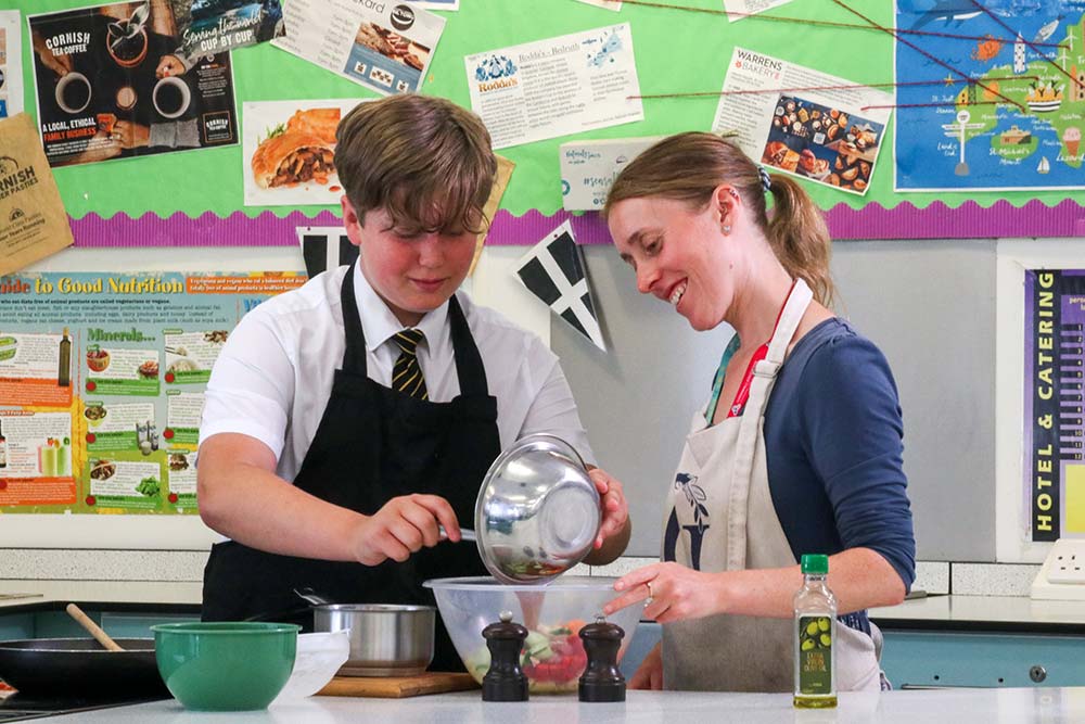 Penrice Open Evening 2025 A picture of a male student making a meal with the help of a teacher in a Hospitality and Catering lesson.